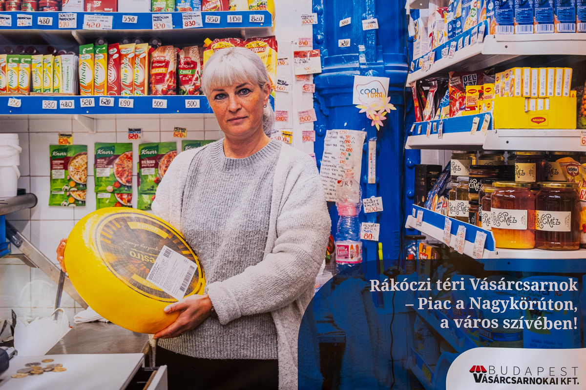 woman in grocery store holding a massive cheese